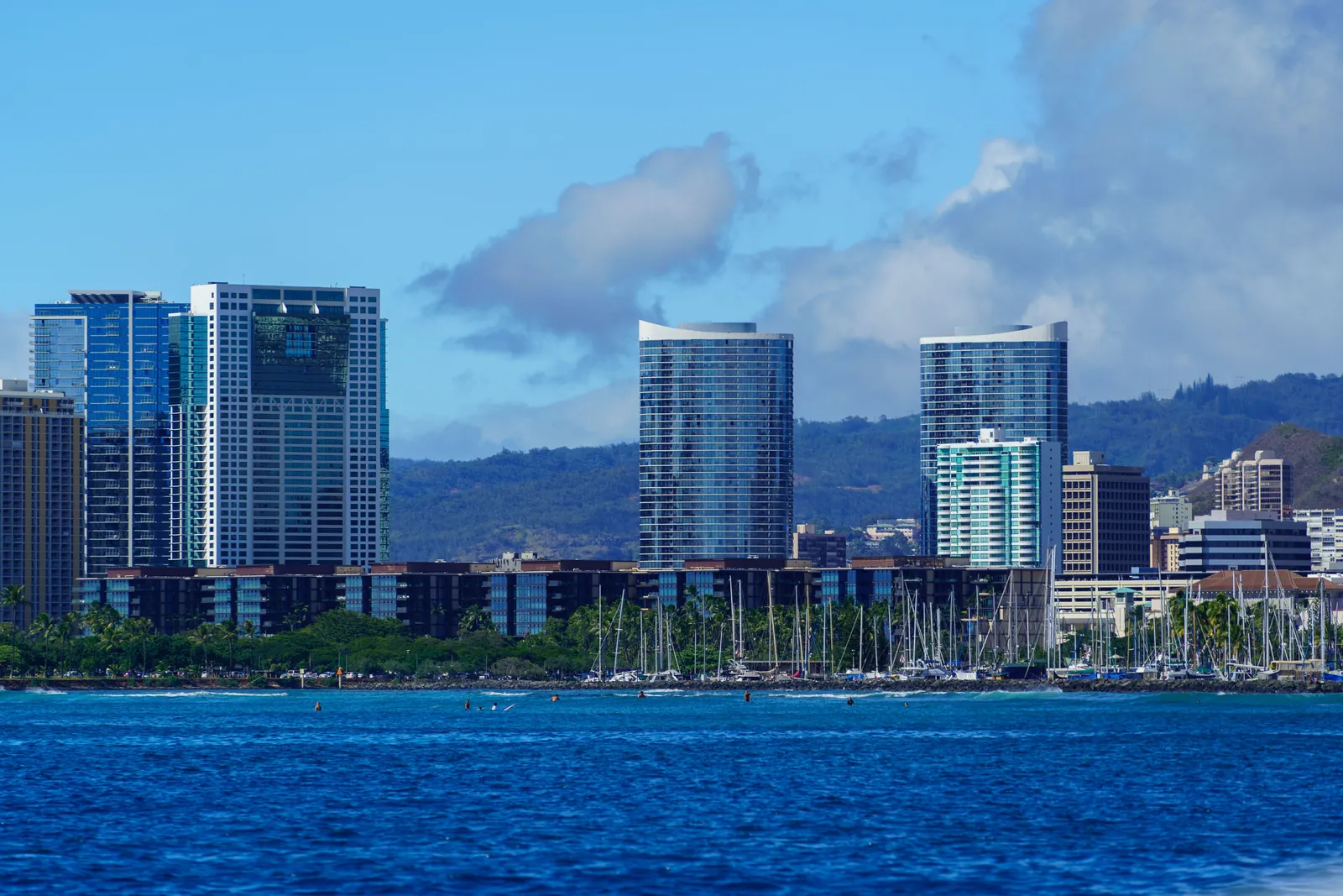 Honolulu skyline rising above an Oahu harbor full of moored sailboat masts