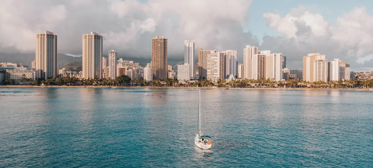 A boat under sail off Waikiki with the Honolulu skyline and Diamond Head in the background, Oahu, Hawaii