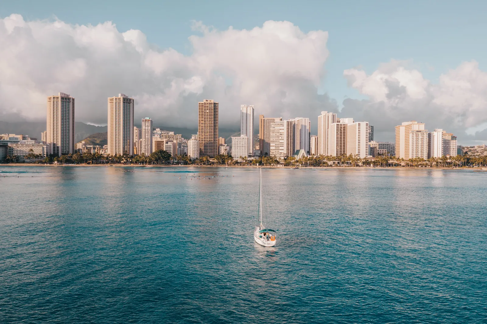 A sailboat off Waikiki with the Honolulu skyline behind, Oahu