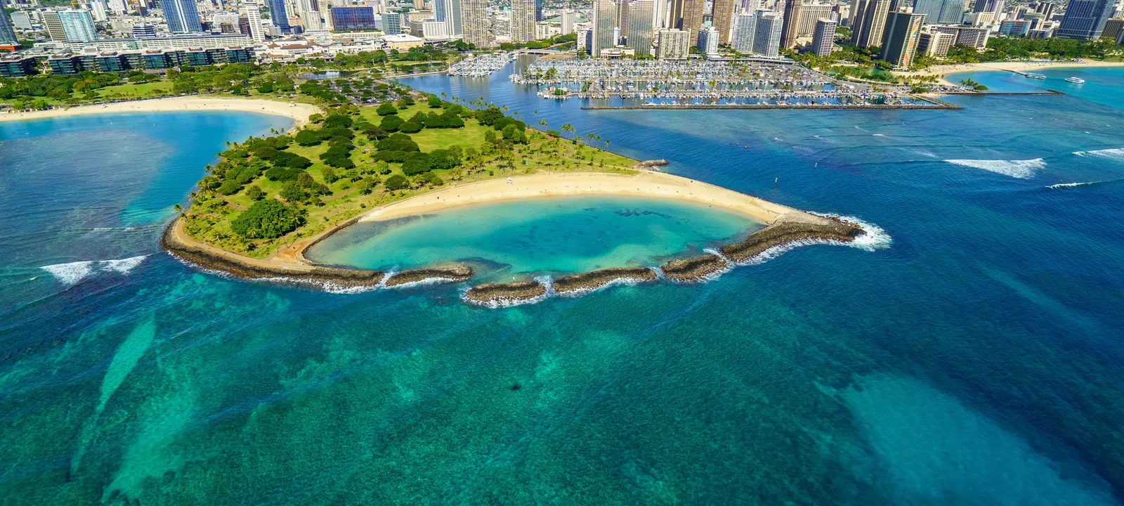 Aerial view of the Ala Wai Boat Harbor full of boats with Magic Island, the Waikiki skyline and the Koolau mountains on Oahu